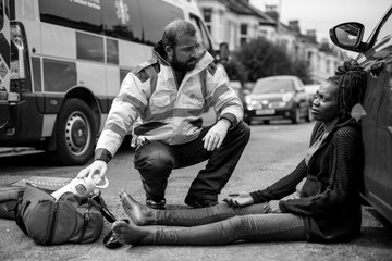 Fototapeta na wymiar Male paramedic checking on an injured woman on a road