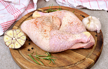 Delicious raw chicken legs or drumsticks on a wooden cutting board. Rustic preparation scene with garlic and raw meat.