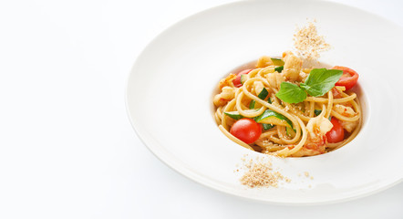 Pasta with shrimps, cherry tomatoes, zucchini and basil on white background