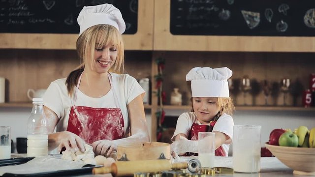 Mom and daughter in the same clothes have fun preparing a dough on a cozy kitchen. They preparing Christmas cookies. Family day, Cooking, Mom and daughter concept