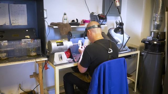 Male jewelry maker hand polishing and buffing a silver ring in a jewellery making workshop.