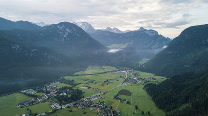 Fototapeta premium Aerial view of the morning foggy landscape in the alpine mountains