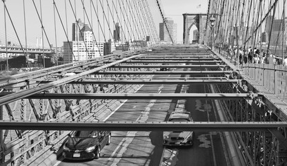 view on Brooklyn bridge and Hudson river with cars running and modern skyline in background in Manhattan, New York