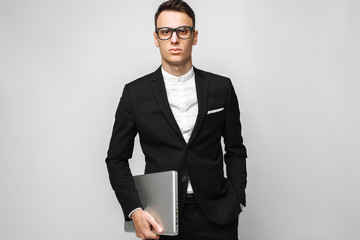 Business man in suit and glasses with laptop isolated on gray background.