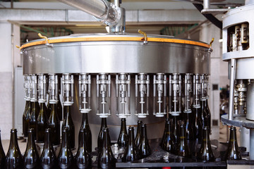 Glass bottles on the automatic conveyor line at the champagne or wine factory. Plant for bottling alcoholic beverages.