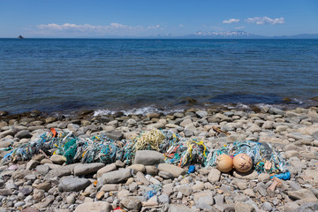 Garbage thrown on the sea shore. Cape Stolbchaty. Cape on the west coast of the island of Kunashir. It is composed of layers of basaltic lavas of the Mendeleyev volcano.