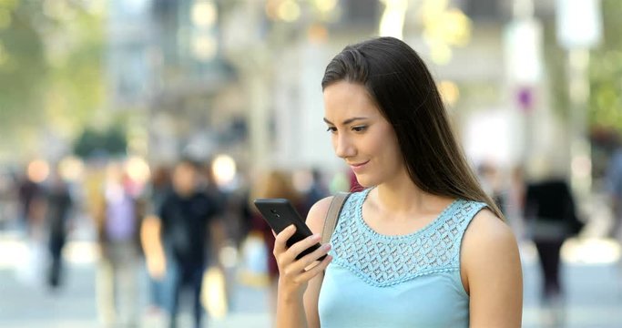 Surprised woman reading smart phone content standing in the street