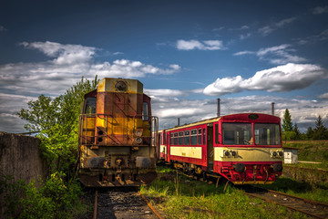 Old diesel locomotive  in train cemetery in the summer with green grass and trees in the background and great cloudy sky