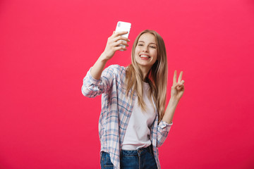 Charming young woman in white hat travel and take selfie on front camera smartphone posing isolated on shine pink background