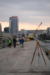 Theodolite at the construction site and the departing builders