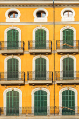 Beautiful old green windows on the yellow wall. Majorca Spain