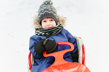 Fototapeta na wymiar The boy sits on a snow saucer in the snow.