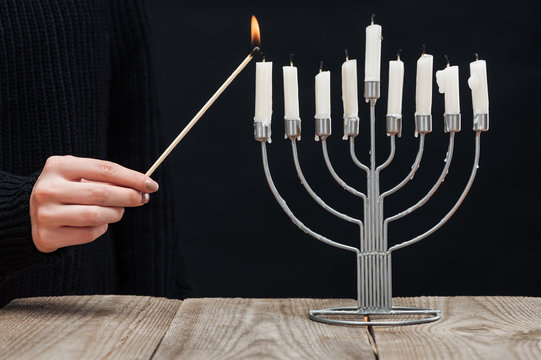 Partial View Of Woman Lighting Candles On Menorah On Wooden Tabletop On Black Backdrop, Hannukah Holiday Concept