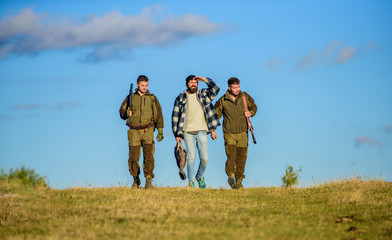 Hunters with guns walk sunny fall day. Brutal hobby. Guys gathered for hunting. Group men hunters or gamekeepers nature background blue sky. Men carry hunting rifles. Hunting as hobby and leisure