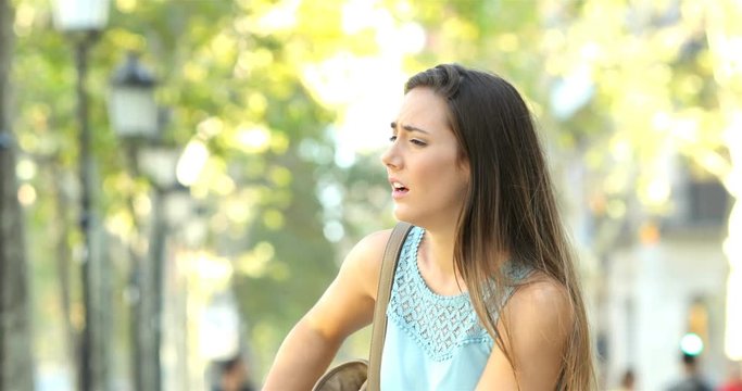 Asthmatic woman suffering an asthma attack and using inhaler in the street