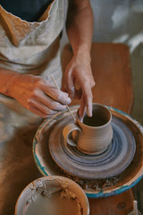 partial view of man decorating clay pot at workshop