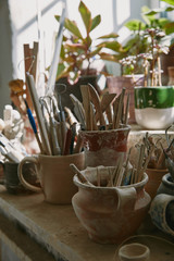 Fototapeta na wymiar selective focus of pottery tools and paintbrushes at table in pottery studio