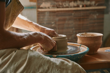 partial view of professional potter working on pottery wheel at workshop - obrazy, fototapety, plakaty