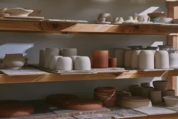Foto op Plexiglas ceramic bowls and dishes on wooden shelves at pottery studio © LIGHTFIELD STUDIOS