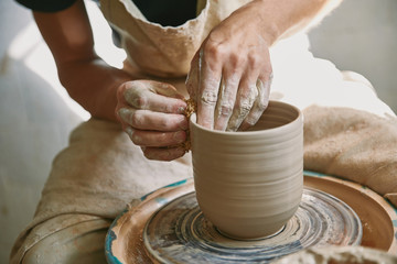 cropped image of male craftsman working on potters wheel at pottery studio - Powered by Adobe