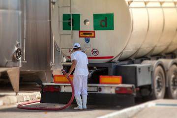 Male worker loading truck container with milk in an industrial cheese production factory