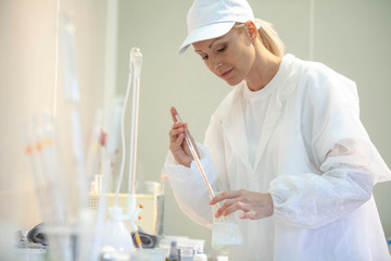 Female lab worker doing tests in a laboratory in an industrial cheese production factory