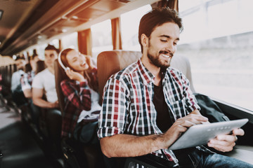Smiling Man Using Digital Tablet in Tourist Bus