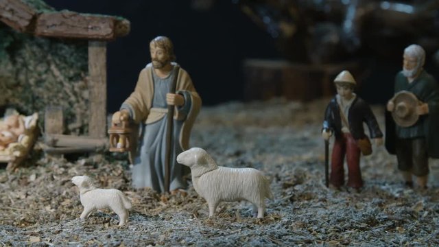 Nativity scene with figurines in the manger including baby Jesus, Mary, Joseph, shepherds and sheeps. Christmas traditions.