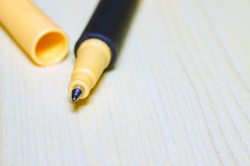 ball pen with a yellow cap on a wooden surface, macro photography. texture background