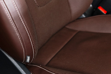 Modern luxury car brown leather interior. Part of leather car seat details with white stitching....