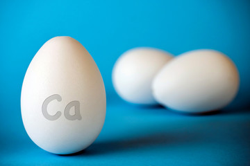 Chicken eggs have calcium CA to strengthen bones, isolated in blue background