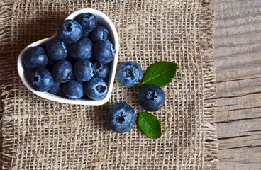 Freshly picked organic blueberries in a heart shaped bowl on a burlap cloth background.
Blueberry. Bilberries.Healthy eating,vegan food or diet concept.Selective focus.