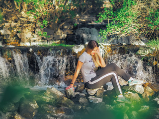 Young girl at the forest happy near waterfall.