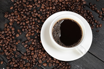 Cup of coffee and beans on wooden background