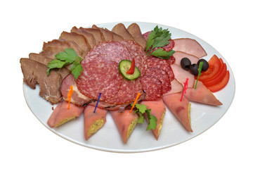 Meat slices with greens, olives and vegetables on a white plate, close-up isolated