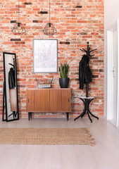 Vertical view of classic hall with brick wall, wooden shelf, mirror and map on the wall, real photo