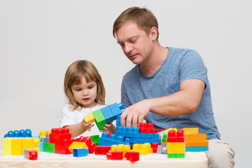 father and child playing with colorful blocks together at home