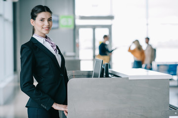 beautiful young woman smiling at camera while working at check-in desk in airport