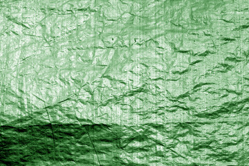 Crumpled transparent plastic  surface in green color.