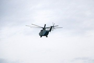 a large military helicopter hovers in the sky. A camouflaged helicopter flies at high speed.