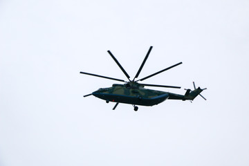 Naklejka na ściany i meble a large military helicopter hovers in the sky. A camouflaged helicopter flies at high speed.