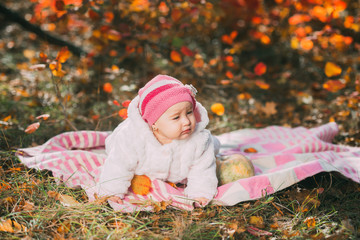 A happy little girl on a blanket in the autumn forest