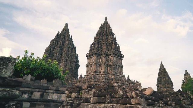 Prambanan temple towers stone brick piles in Jogjakarta, Indonesia on cloudy evening, slide right