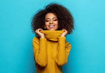 Smiling black woman wear yellow cardigan isolated on blue background