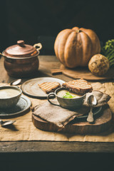 Autumn, Winter home dinner. Fall warming celery cream soup in cup and toast over yellow linen tablecloth, fresh pumpkin at background. Comfort food, vegan, vegetarian, healthy and slow food concept