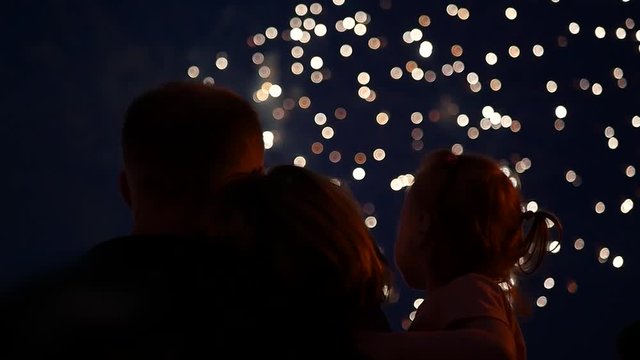 Friendly family with a daughter in their hands are watching fireworks in the night sky. slow motion, 1920x1080, full hd