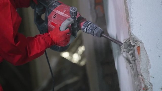 worker with demolition hammer breaking interior wall