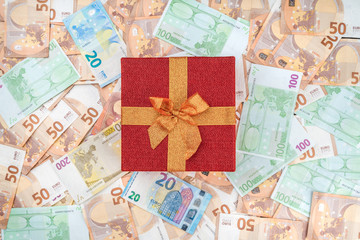 On background of European money of different value a valuable gift for loved ones. Top view.