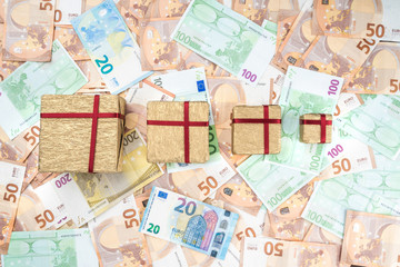 Fototapeta na wymiar On background of European money of different value. Gifts of different sizes. Top view.