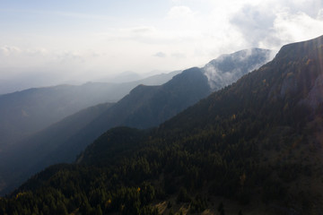 Aerial photography over big mountain forest. Sunset over the forest. Foggy valley at the sunrise. Golden hour over the forest with mist. Beautiful aerial landscape. Drone shots over the foggy forest. 